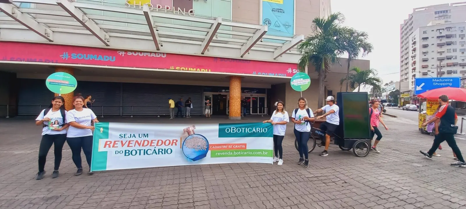Representantes de marca da Exfera Mídia com faixa O Boticário em frente ao Madureira Shopping, Rio de Janeiro